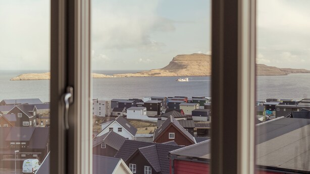 A coastal town with houses and a prominent hill in the background. - Charming Artistic Retreat | Panoramic View (Hoyvík)