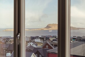 A coastal town with houses and a prominent hill in the background.