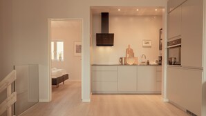 A modern kitchen with a central island, built-in oven, and a large range hood. - Charming Artistic Retreat | Panoramic View (Hoyvík)