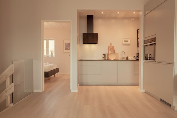A modern kitchen with a central island, built-in oven, and a large range hood.