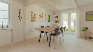 A dining area with a wooden table and chairs, white walls, and artwork. - Charming Retreat In The Heart Of Tórshavn (Tórshavn)
