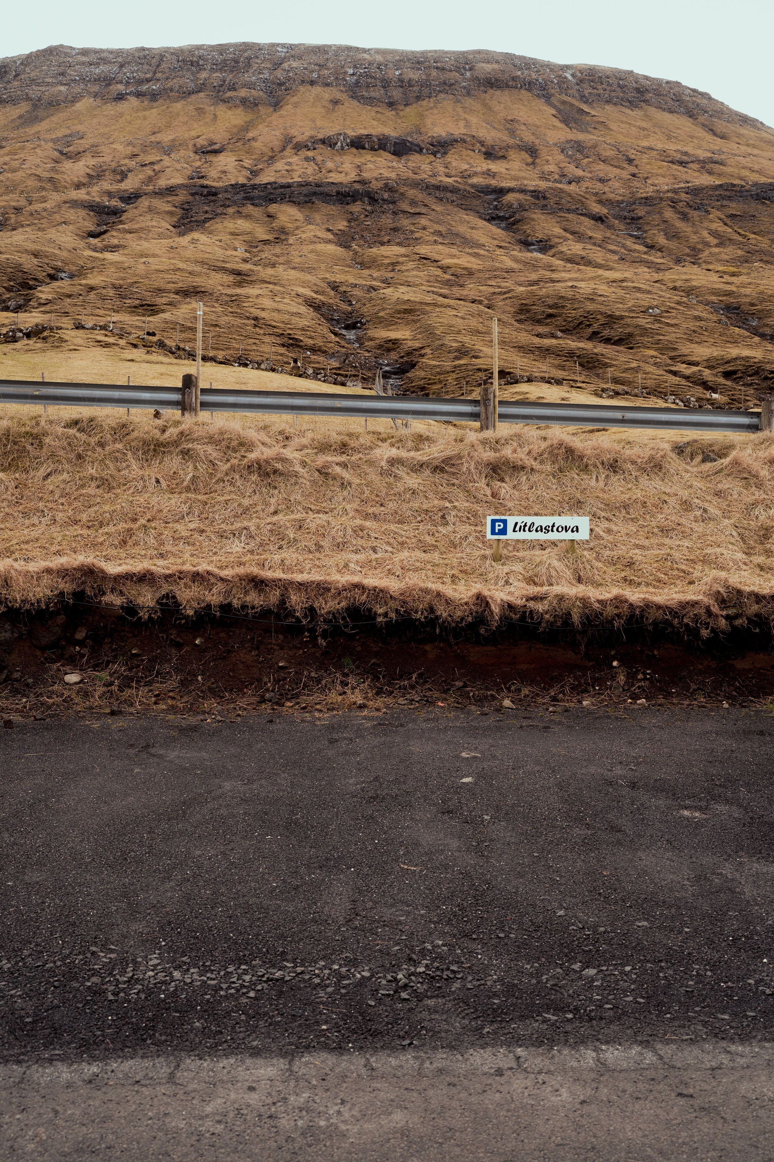 A parking sign for Liteastova on a roadside with a mountain in the background.