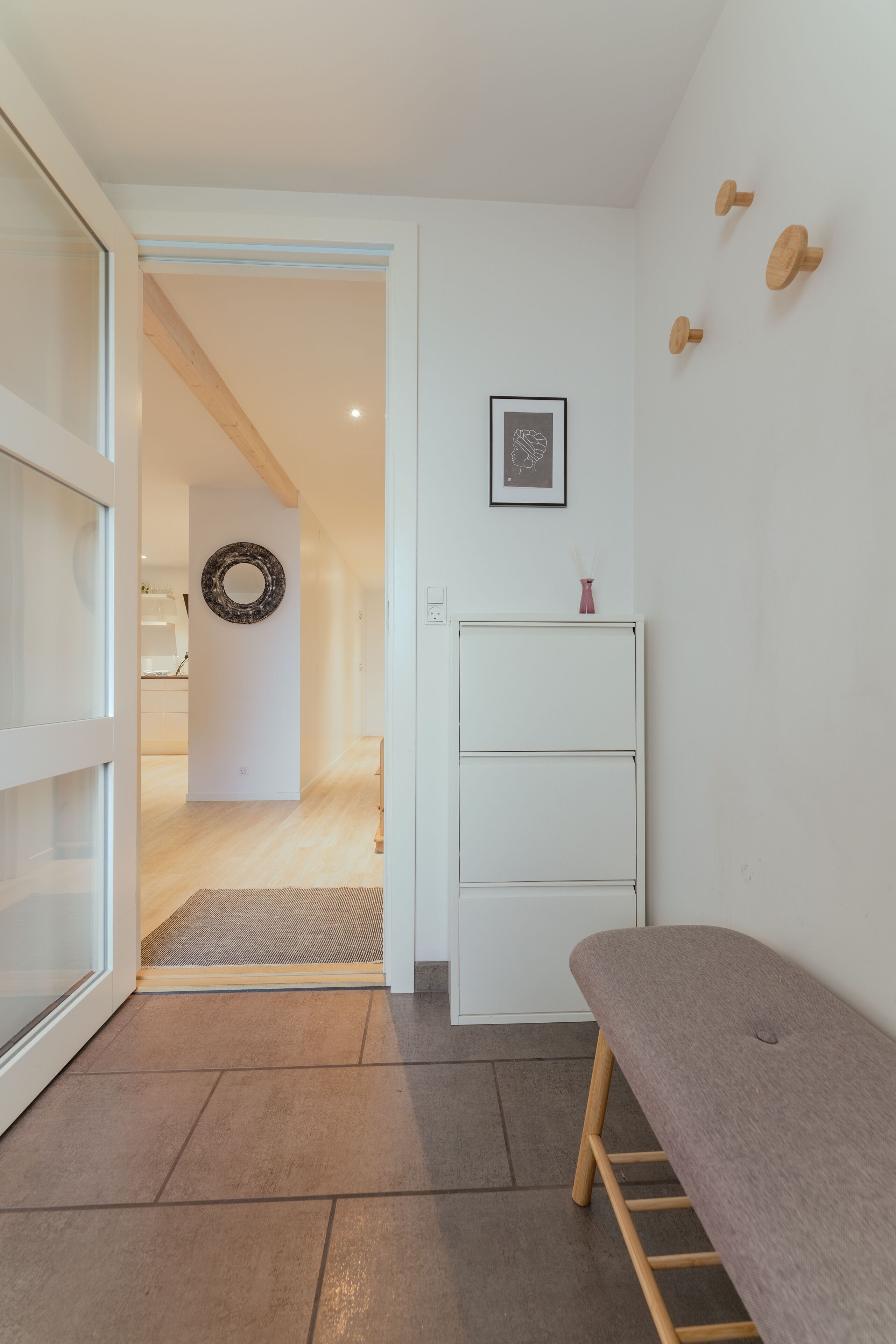 A hallway with a bench, a wall-mounted mirror, and a small cabinet.