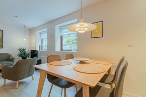 A dining area with a wooden table, four chairs, and a hanging pendant light. - Central Apartment In Tórshavn | Private Parking (Tórshavn)