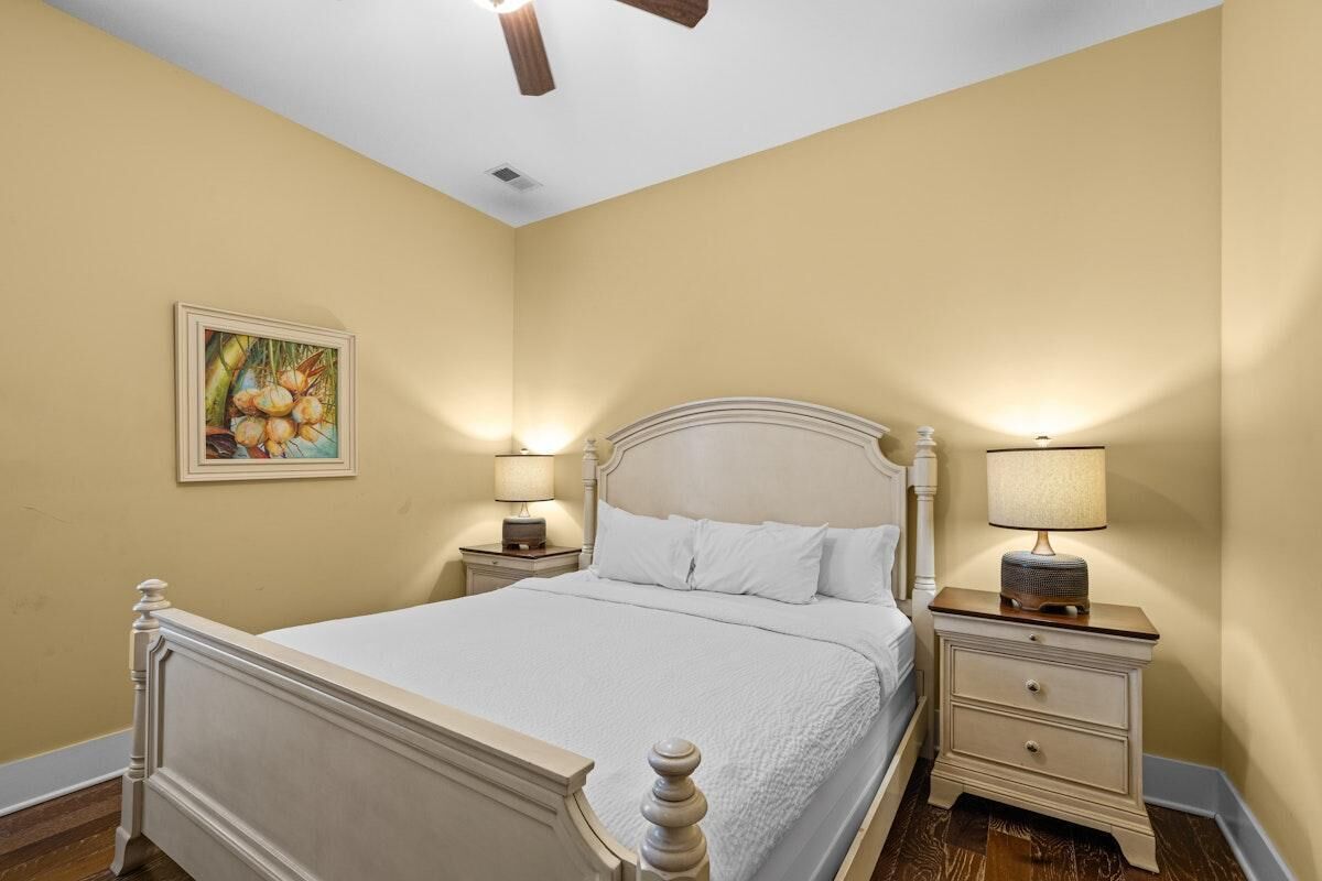 Ein Schlafzimmer mit Bett, Nachttischen, einem Deckenventilator und einem Bild an der Wand.