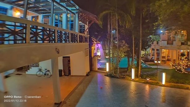 Vista nocturna de un hotel con un paseo techado, una cascada y zonas exteriores iluminadas.