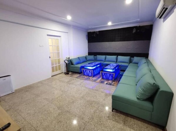 A living room with a green sofa, two blue cube-shaped side tables, and a patterned rug.
