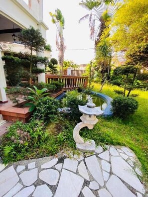 A garden with a stone pathway, a small pond, and various plants.