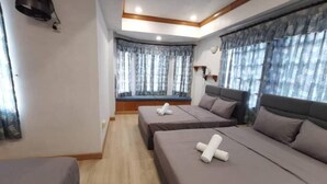 Habitación de hotel con dos camas, un asiento junto a la ventana y una lámpara en el techo.