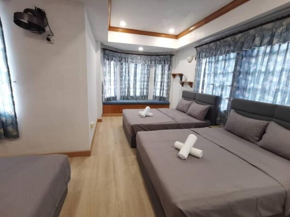 Een hotelkamer met twee bedden, een raamzitje en een plafondlamp.