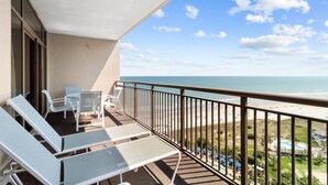 Un balcon avec des fauteuils et une vue sur la plage.