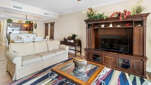 Un salon comprenant un canapé, une table basse, un meuble pour la télévision et un ventilateur de plafond.