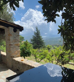 Un bâtiment en pierre doté d’un toit rustique, d’un mur en pierre et offrant une vue sur un vignoble et des montagnes lointaines.