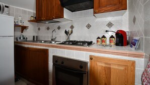A kitchen with wooden cabinets, a stainless steel stove, a sink, and a coffee maker.