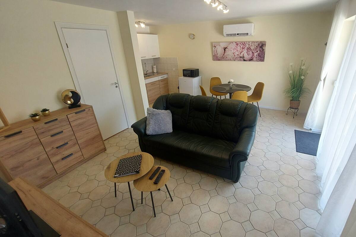 Ein Wohnzimmer mit einer Couch, einem Couchtisch, einem Fernseher und einem Essbereich mit Stühlen.