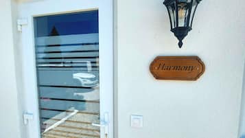 Una puerta con un panel de vidrio y una señal de madera que dice "Harmony" en la pared de al lado.
