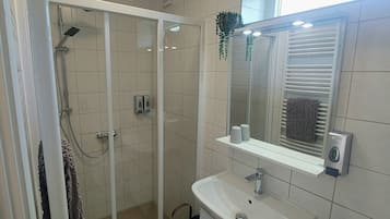 A modern bathroom with a glass-enclosed shower, a sink with a mirror above it, and a towel rack.