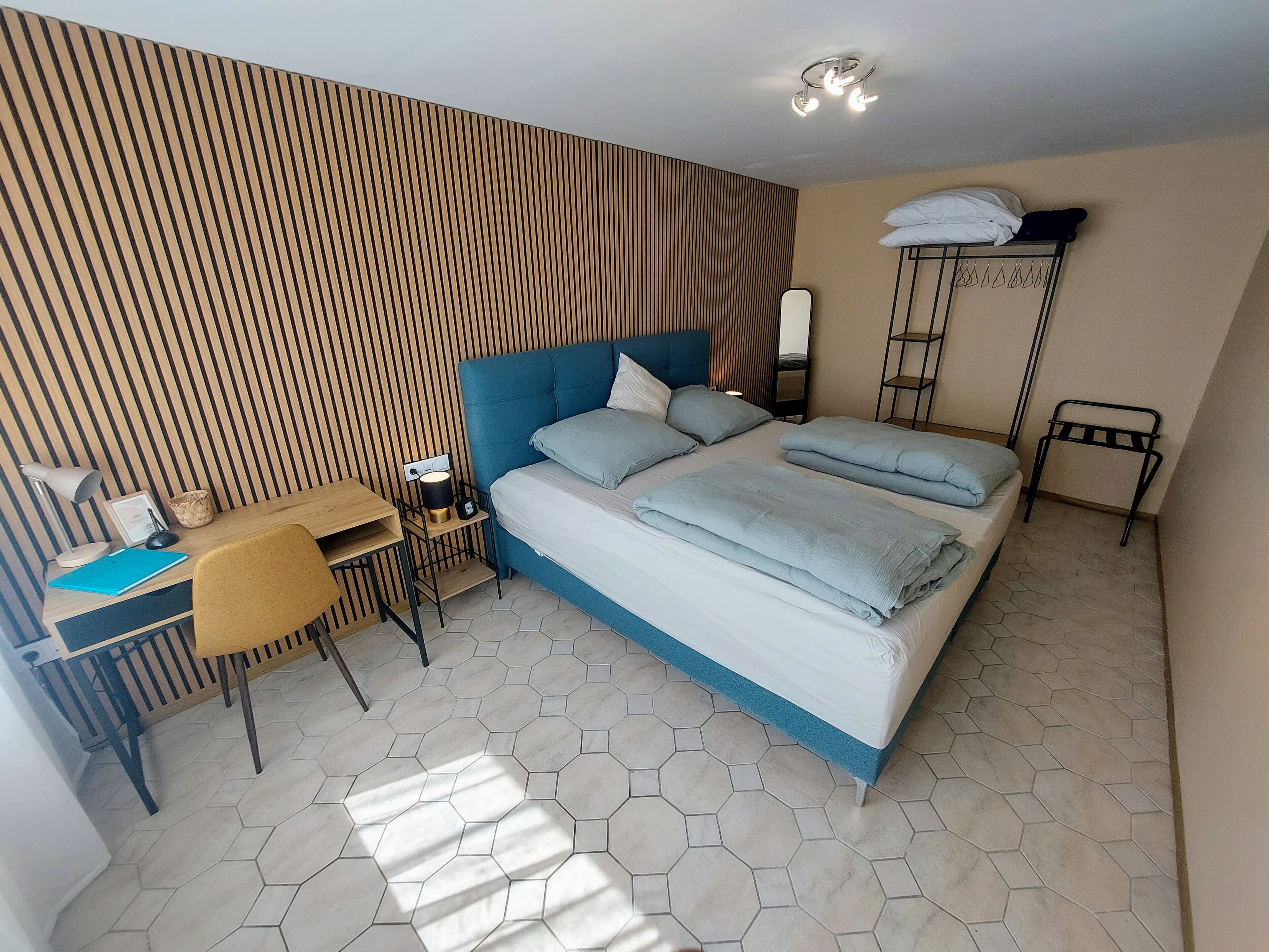 Una habitación de hotel moderna con una cama grande, un escritorio con silla, una mesita y un armario.