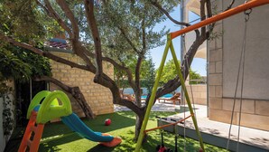 Ein Kinderspielbereich mit Rutsche, Schaukeln und Rollern.