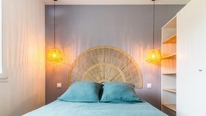 A bedroom with a bed, two wall-mounted lamps, and a built-in shelving unit. - Charming Modern Bungalow with Nordic Hot Tub, Near Beach and Amenities in Saint-Jean-de-la-Rivière (Saint-Jean-de-la-Rivière)