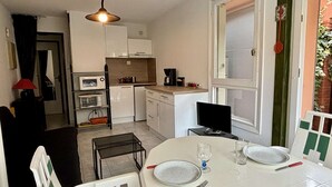 A compact kitchen with white cabinets, a microwave, a coffee maker, and a dining table set for two.
