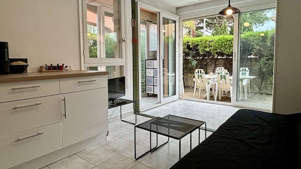 A compact kitchen with white cabinets, a black countertop, and a sliding glass door leading to a patio with outdoor furniture.