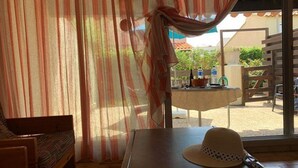 A room with a wooden table, a hat, and a view of an outdoor area with a table and chairs. - Charming 3-Room, 6 Pers., Sea Front, Parking (Cap d'Agde)