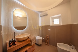 A bathroom with a large oval sink, a mirror, a toilet, and a bathtub. - TD Trulli Benedetta w Pool in Peaceful Nature (Castellana Grotte)