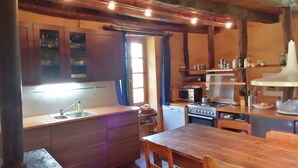 A compact kitchen with wooden cabinets, a sink, a microwave, and a stove. - Natuurhuis (Orliac)
