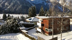 A cabin with a wooden exterior, a sloped roof, and a view of snow-covered mountains. - Apartment Silver Moon (Leutasch)