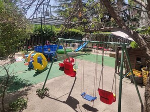 Un terrain de jeux équipé de balançoires, de toboggans et de diverses structures ludiques.