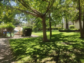 A park with a paved walkway, trees, and a grassy area.