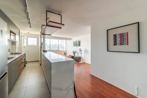 A modern kitchen with a central island, built-in appliances, and a large window providing natural light. - Spacious 2BR Apartment in Prime Location with Pool (Las Condes)