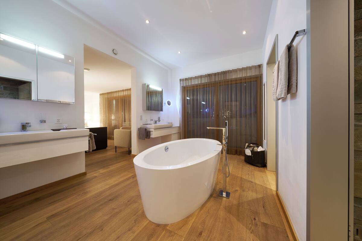A modern bathroom with a freestanding bathtub, a vanity with a mirror, and a shower area.