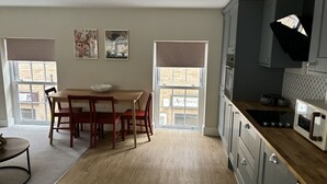 Eine moderne Küche mit Essbereich, großen Fenstern und Blick auf die Straße.