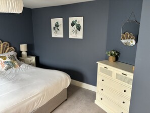 A bedroom with a bed, nightstands, a dresser, and wall art.