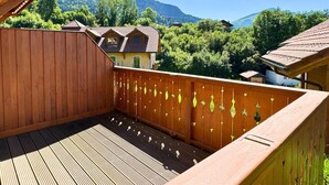 Une terrasse en bois offrant une vue sur une montagne et une maison.