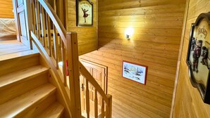 Un escalier en bois avec une rampe, des murs en bois et un tableau encadré représentant une danseuse.