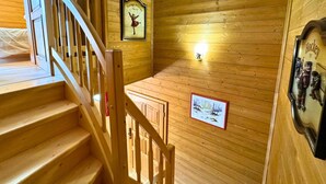 A wooden staircase with a handrail, wooden walls, and a framed picture of a dancer.