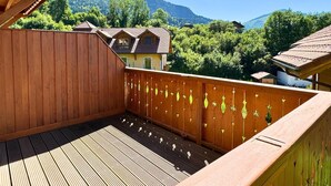 A wooden deck with a view of a mountain and a house.