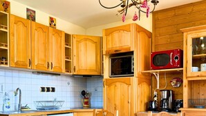 A wooden kitchen with a dining table and chairs, a microwave, and various kitchen appliances. - Z-Chalet Mitoyen 5B., Z-Chalet Mitoyen 5B. (Mont-Saxonnex)