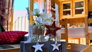 A rustic wooden table with a decorative centerpiece featuring white flowers and red stars, set against a window with curtains. - Z-Chalet Mitoyen 5B., Z-Chalet Mitoyen 5B. (Mont-Saxonnex)