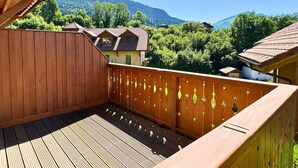 A wooden deck with a view of a mountain and a house. - Z-Chalet Mitoyen 5B., Z-Chalet Mitoyen 5B. (Mont-Saxonnex)