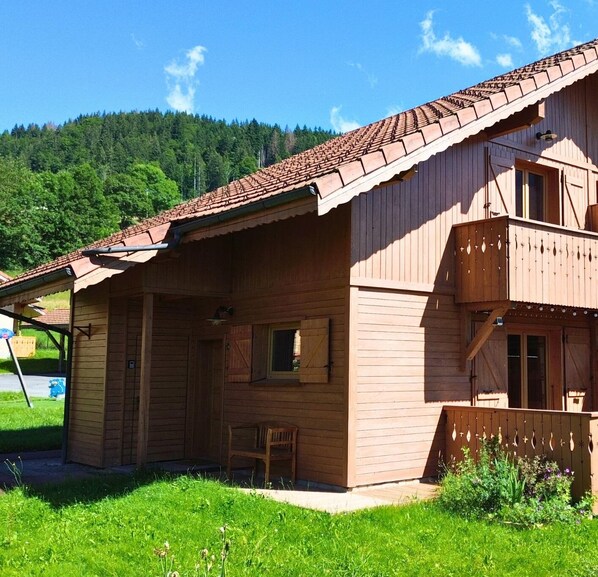 Un chalet en bois doté d’un toit à pente, d’un balcon et d’un petit espace porche.