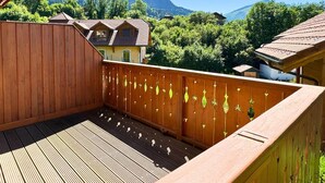 Eine Holzterrasse mit Blick auf einen Berg und ein Haus.