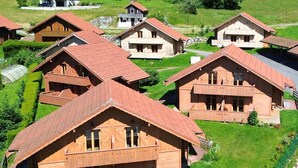 Eine Gruppe Holzhütten mit Satteldächern, umgeben von üppigen grünen Feldern und Bäumen.