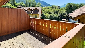 Terraza de madera con vista a una montaña y una casa.