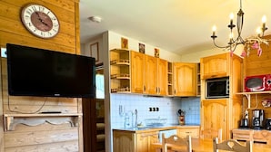 Una cocina acogedora con armarios de madera, una mesa de comedor y un televisor montado en la pared.