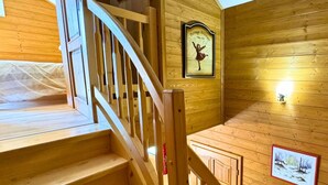 Una escalera de madera con barandilla, paredes de madera y un cuadro enmarcado de una bailarina.