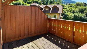 A wooden deck with a view of a mountain and a house. - Z-Chalet Mitoyen 6A., Z-Chalet Mitoyen 6A. (Mont-Saxonnex)